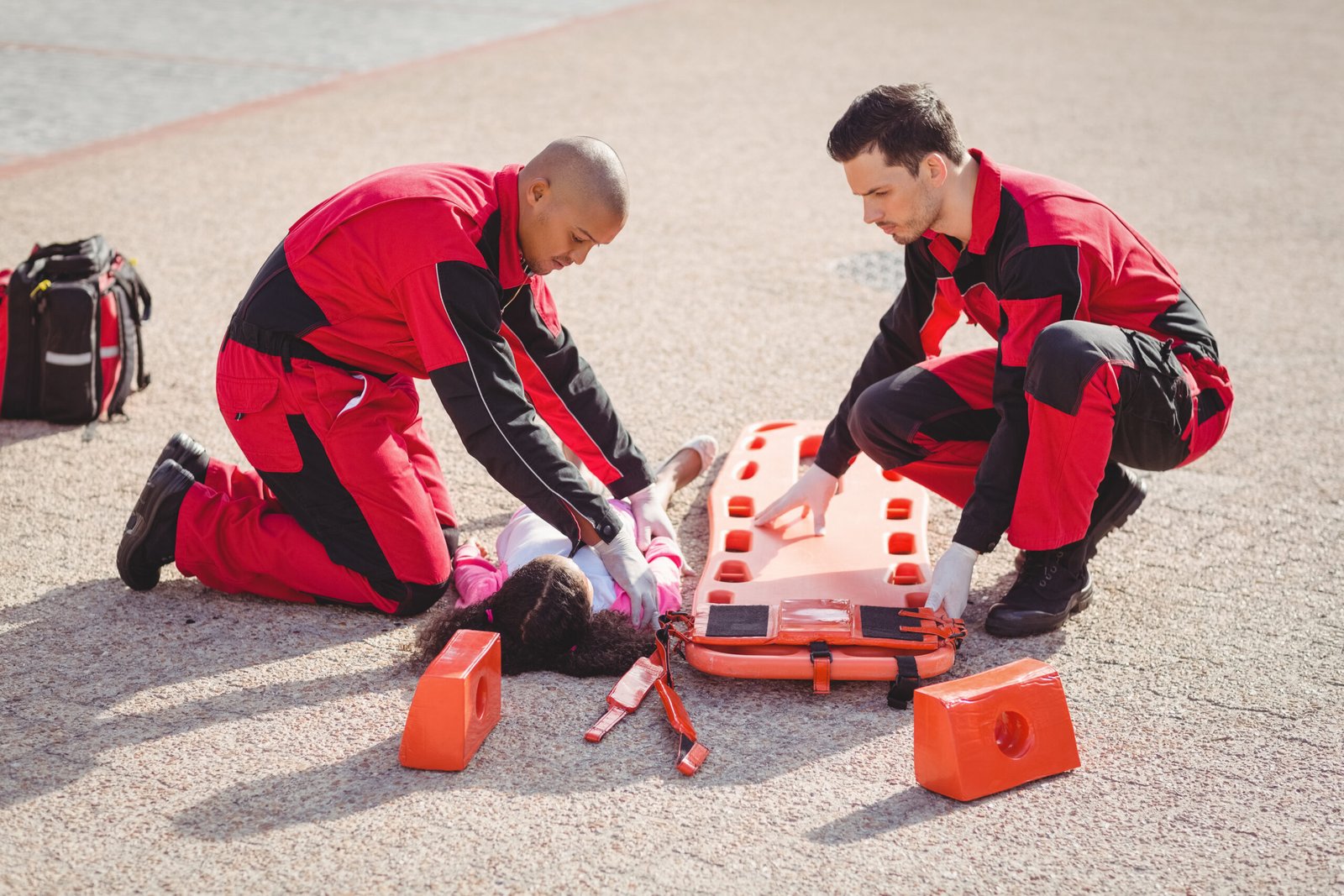 Paramedics putting injured girl onto a backboard on street