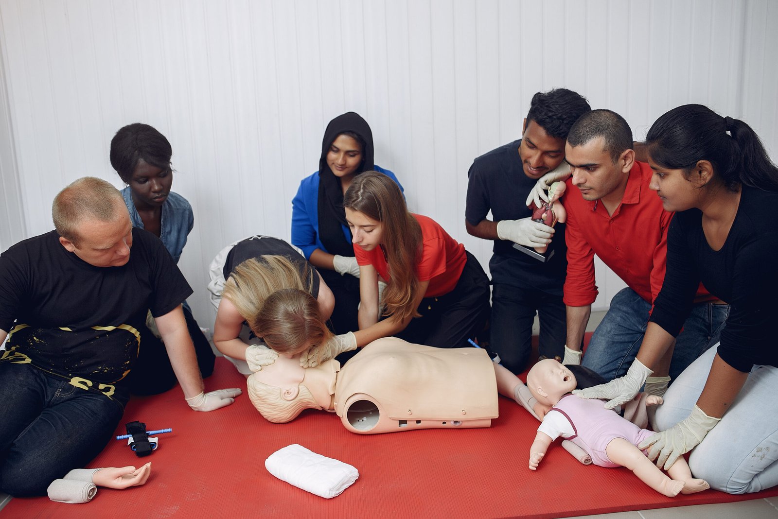 People are practicing medicine.Men and women are learning how to properly provide first aid.