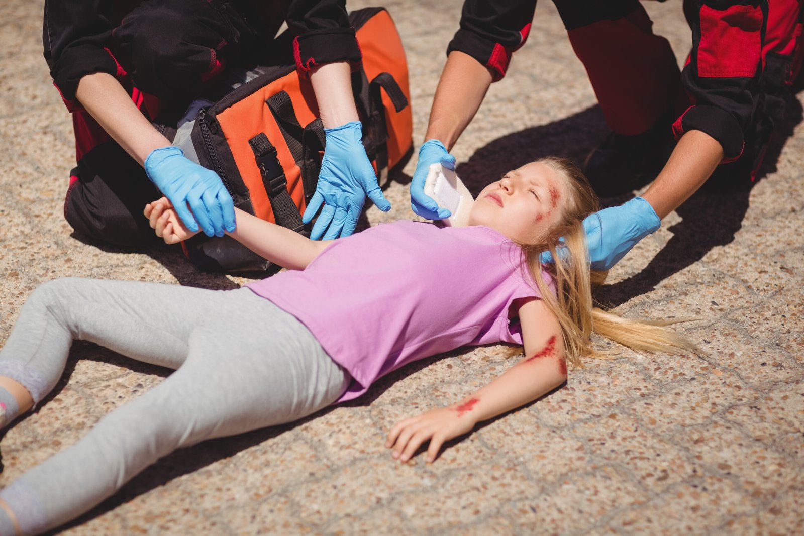 Paramedics examining injured girl on street